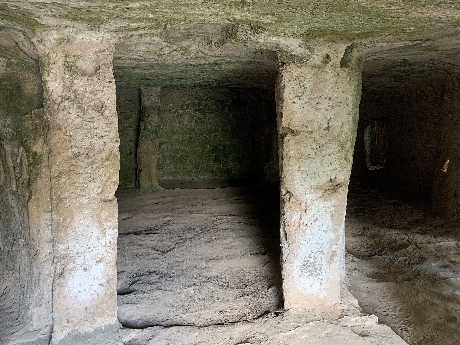 Interno di una grotta scavata nella roccia della gravina della Madonna della Scala, con pilastri risparmiati nel calcare e luce che entra di lato